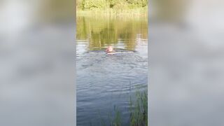 Transgirl swimming in clothes in lake wearing all black: pantyhose, skirt and top. Wetlook in lake.