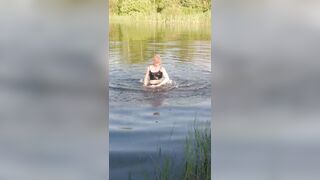 Transgirl swimming in clothes in lake wearing all black: pantyhose, skirt and top. Wetlook in lake.