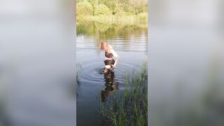 Transgirl swimming in clothes in lake wearing all black: pantyhose, skirt and top. Wetlook in lake.